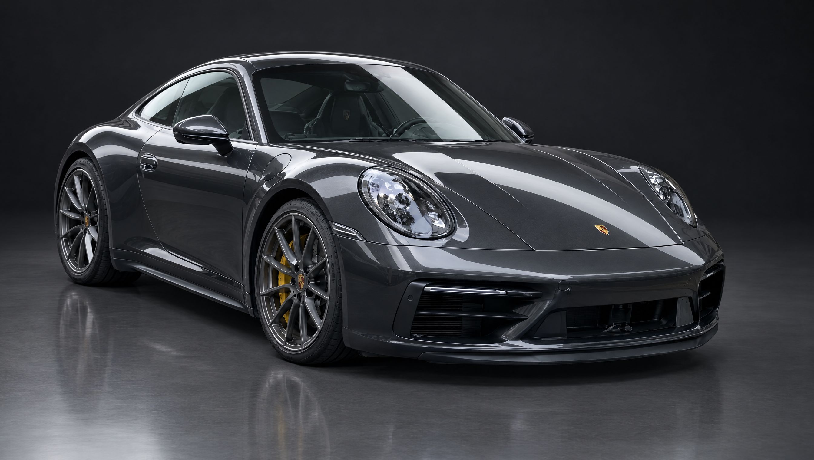 The same graphite sports coupe with its background replaced by a dark car photo studio background
